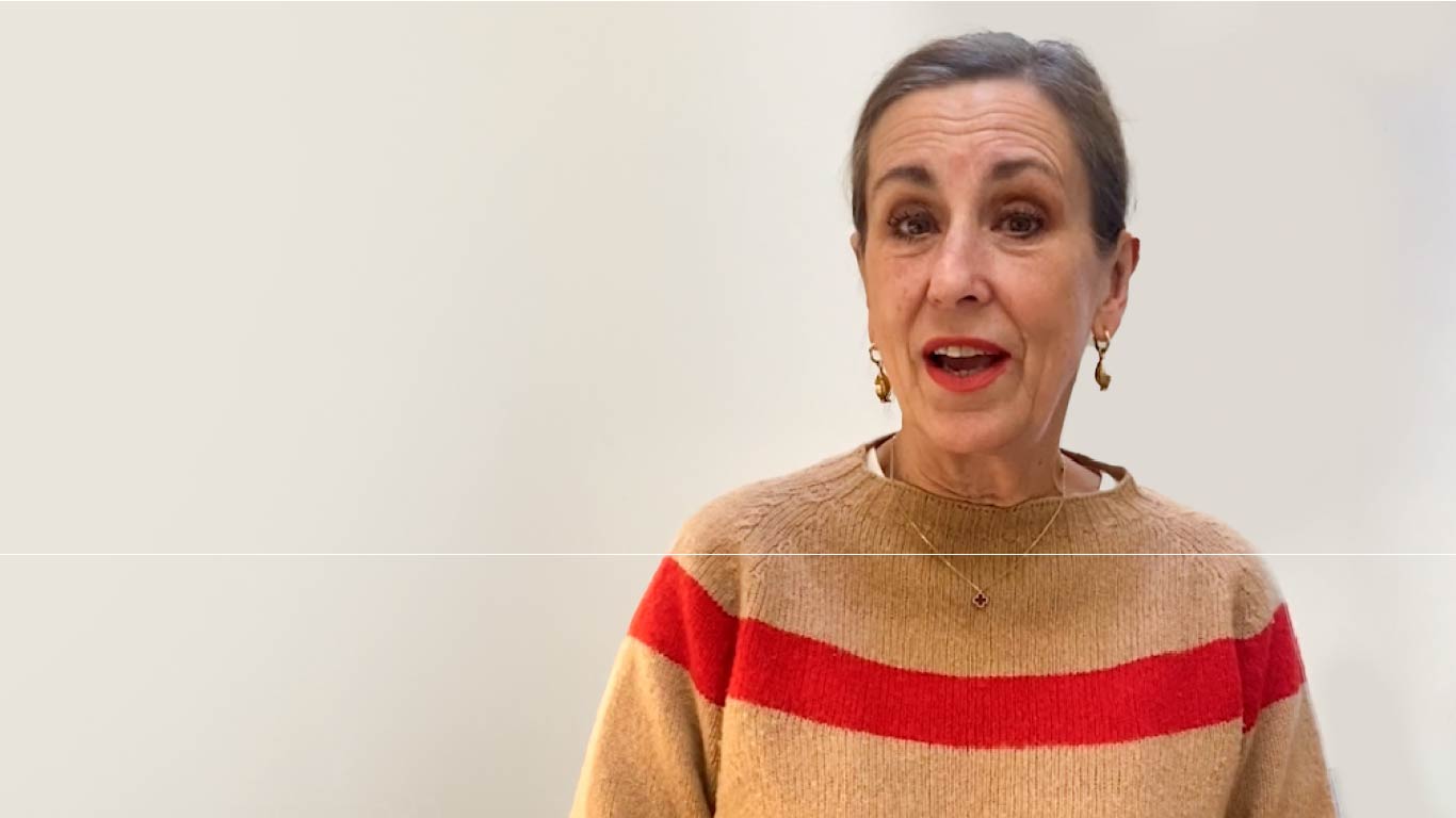 Television presented Kirsty Wark standing in front of the camera speaking wearing brown and red jumper